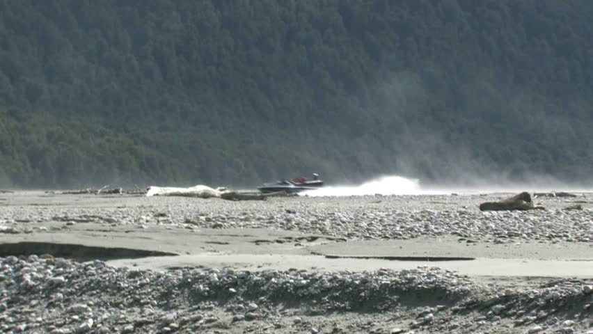 QUEENSTOWN, NEW ZEALAND - CIRCA JULY 2011: Jet boat with tourists travelling at fast speed down the braided Dart River circa July 2011 in Queenstown, New Zealand.