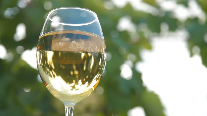 Blue sky with clouds reflected in the glass of wine