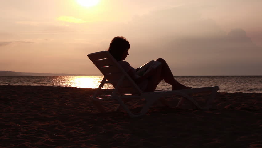 Mother and daughter hugging and kissing on a lounge by the sea. Sunrise in the background.