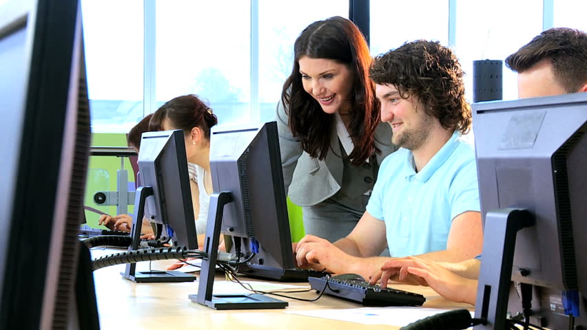 Female college lecturer teaching online young multi ethnic students in computer room