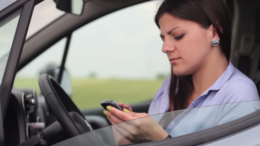 Young attractive woman using mobile phone in the car