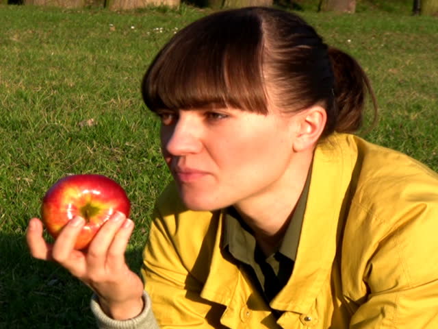 young woman eats fresh apple outdoor