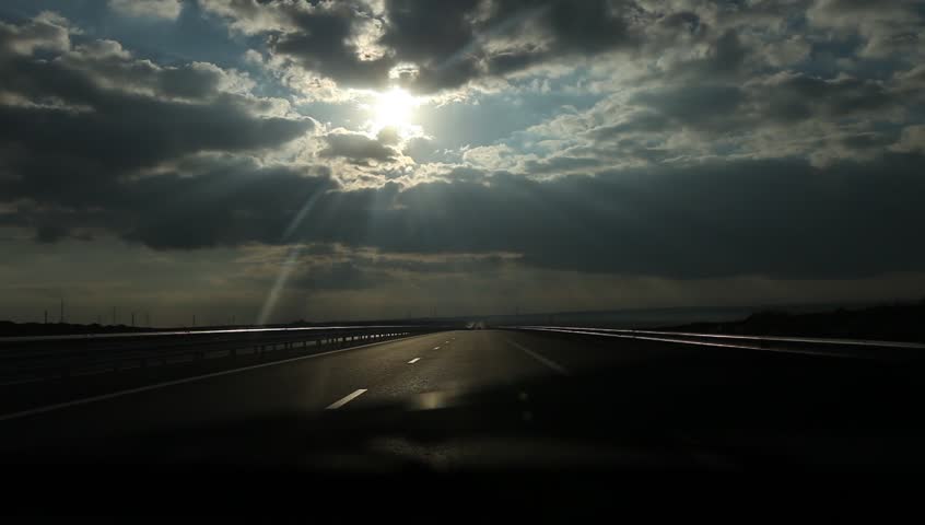 Can runs on highway at sunrise and passes under bridges or crossroads. Dramatic sun and clouds look.
