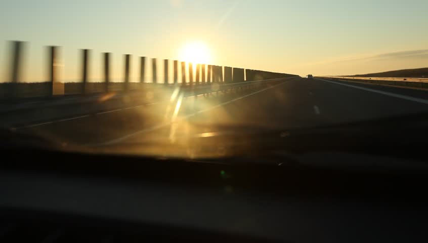 Can runs on highway at sunrise and passes under bridges or crossroads. Dramatic sun and clouds look.
