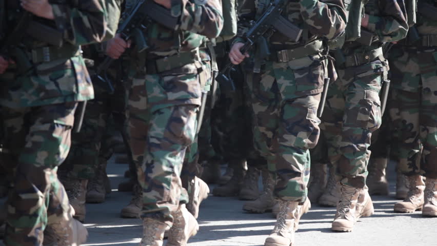 Soldiers marching on a paved road. 