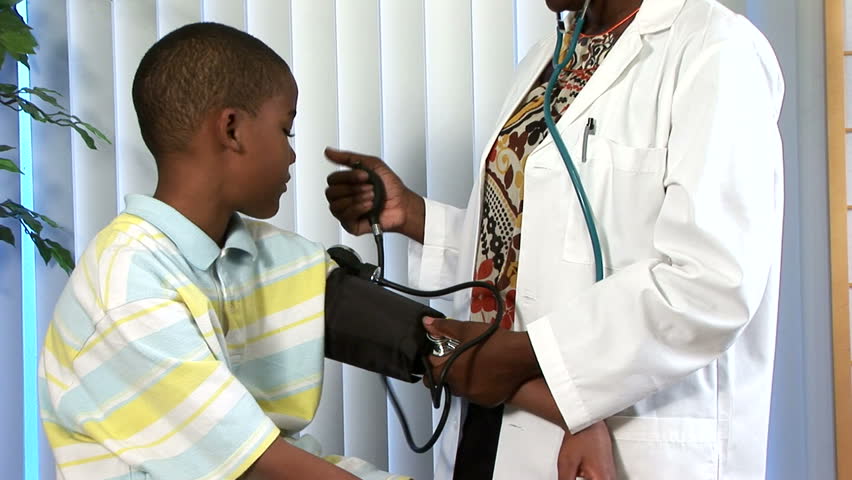 Camera tilts up to reveal woman who appears to be a doctor taking a childÃÂ¢??s blood pressure.