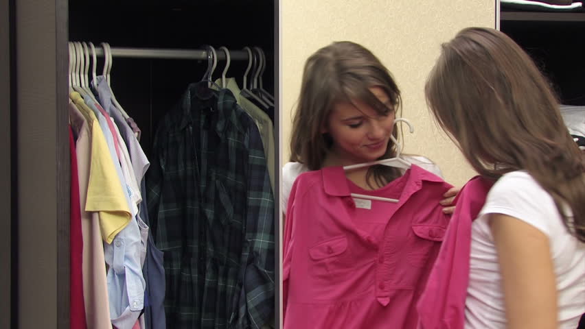 gorgeous woman takes pink shirt of a hanger checks her out in the mirror with satisfaction
