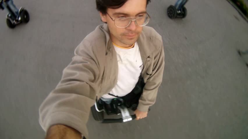 Man wearing spectacles goes on footpath on segway in afternoon