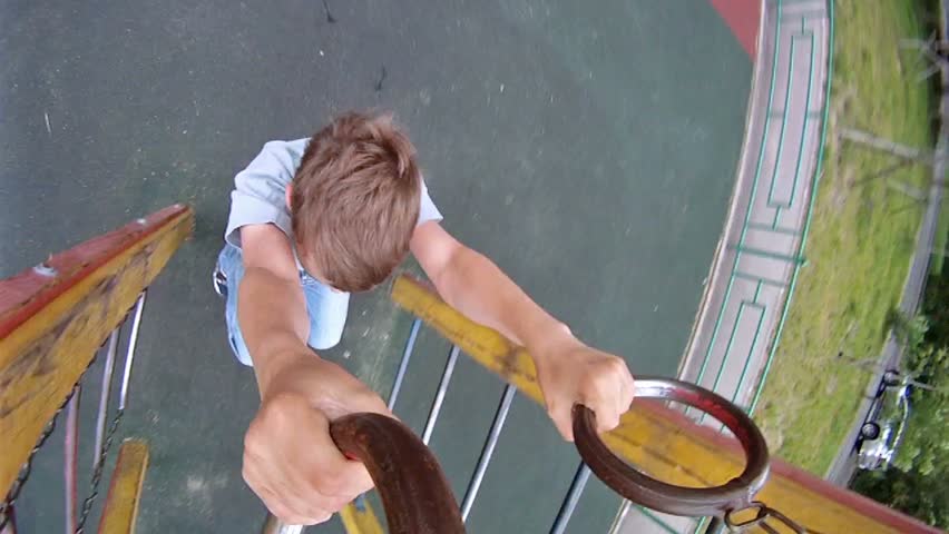 Boy hang on sports rings at playground in house yard
