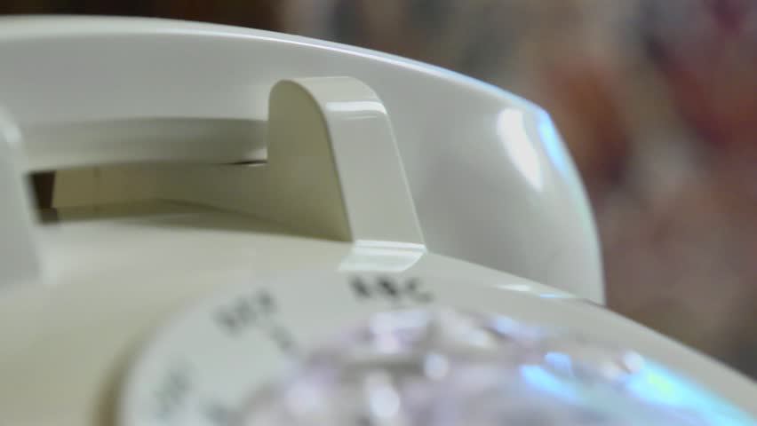 Closeup shallow depth of field shot of someone dialing an old rotary style telephone.