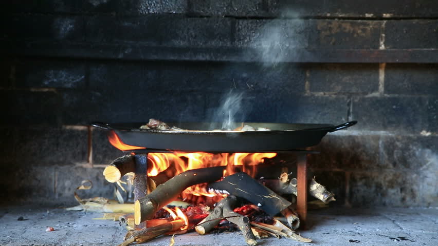 preparing large dish of paella with firewood (chicken)