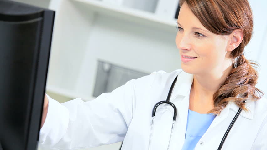 Portrait young female hospital doctor using computer to input data on clinical trials