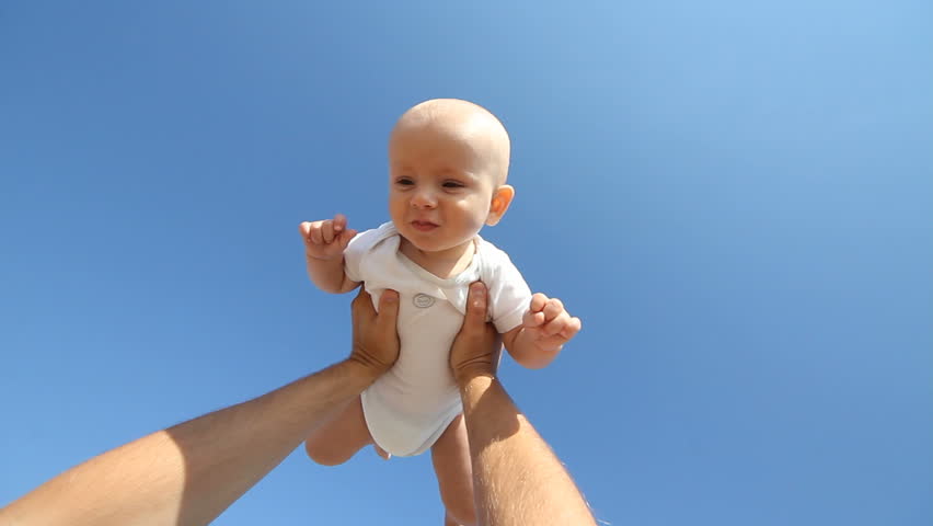 Baby raised in the blue sky by his father's hands
