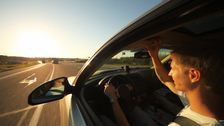 guy at wheel of car going on highway on declining sun