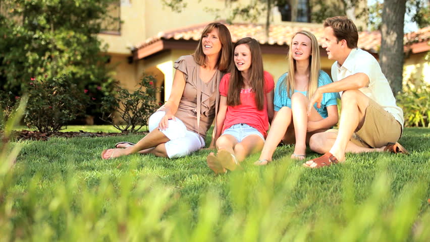 Happy young family spending time together on lawn of family home