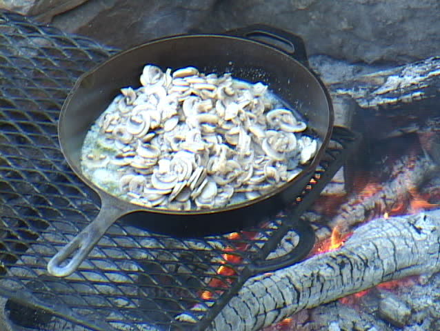 Mushrooms cooking in a cast iron skillet