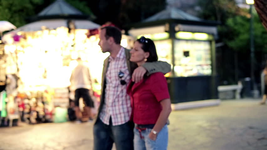Young couple walking together in night city, steadycam shot
