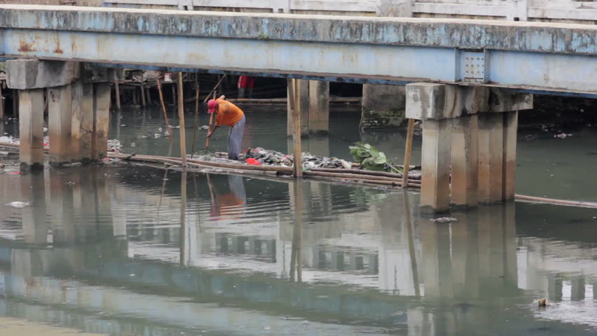 a man working in unhealthy open sewer of Jakarta