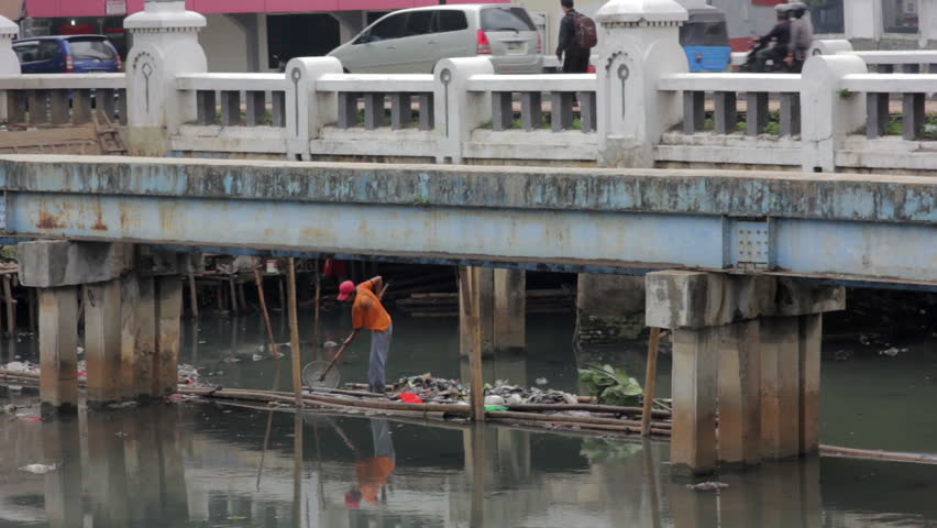 Indonesian man working in unhealthy open sewer of jakarta