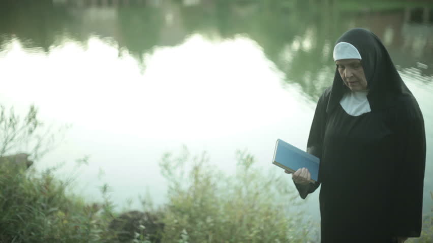 nun walking by the lake