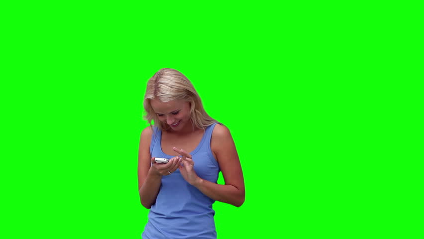 Woman walks in before looking at her phone against a green background