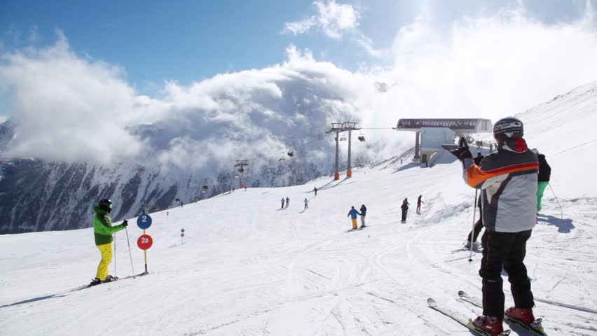Skiers stand near ropeway station in sunny weather