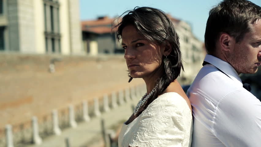Just married couple in disagreement standing on the bridge in Venice 
