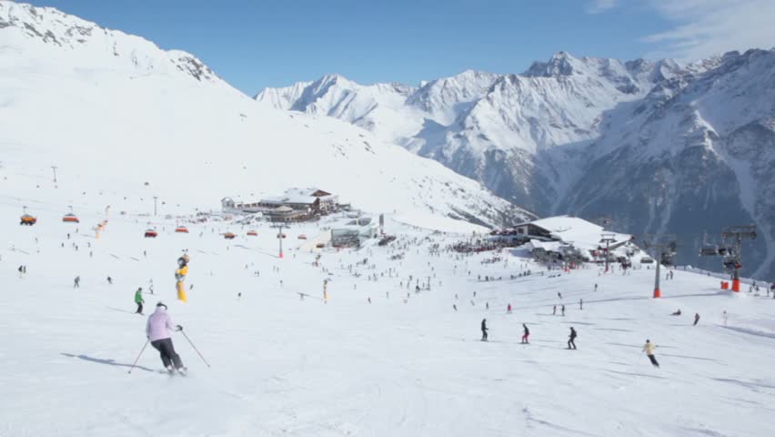 People ride ski and snowboard near cableway, panoramic motion on Austrian Alps at winter day