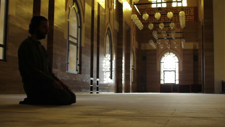 a muslim man worships in a mosque