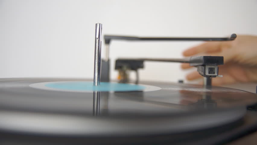 Person lowering needle to play vinyl record on retro turntable close up HD 1080p
