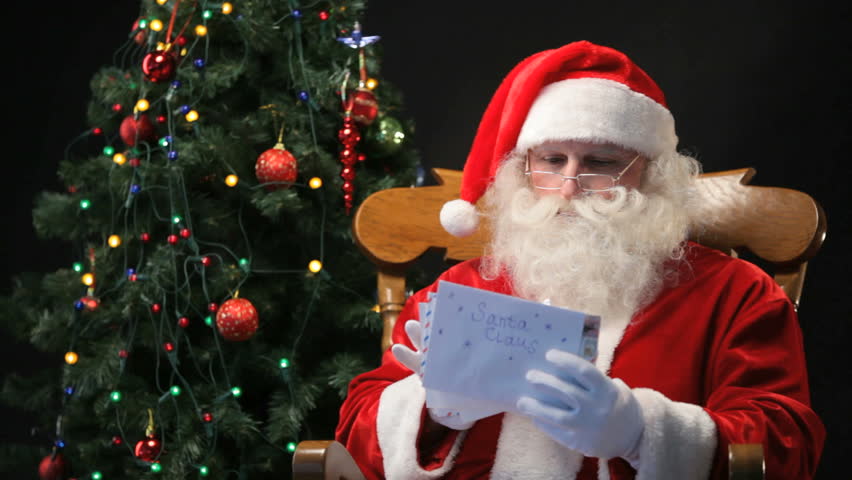 Santa Claus sitting in the chair and reading Christmas letters sent by children