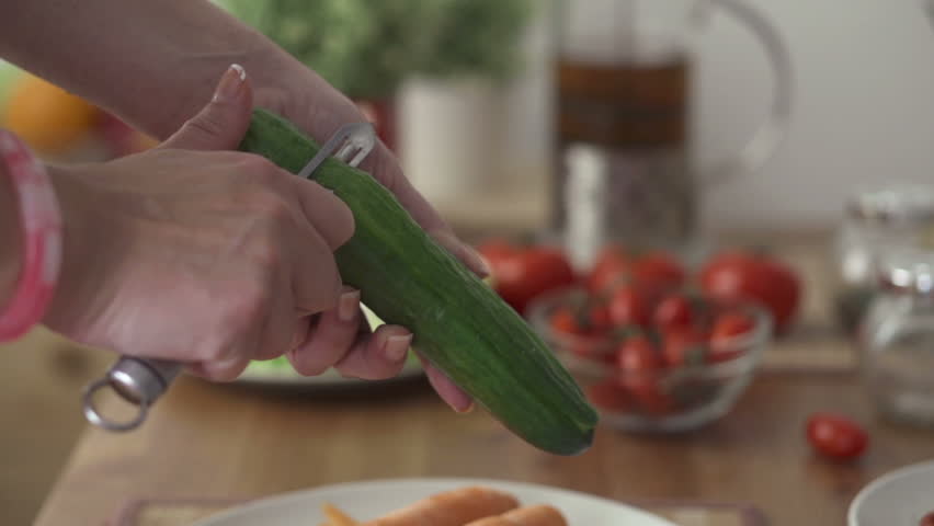 Female hands peeling cucumber, slow motion shot at 240fps
