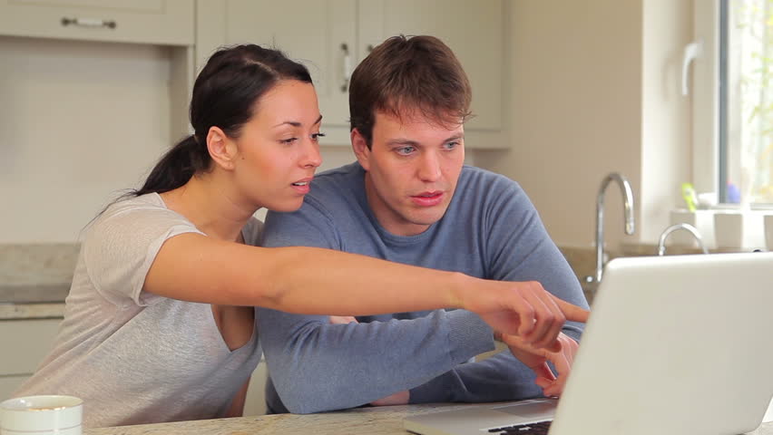 Couple looking at laptop and talking in kitchen