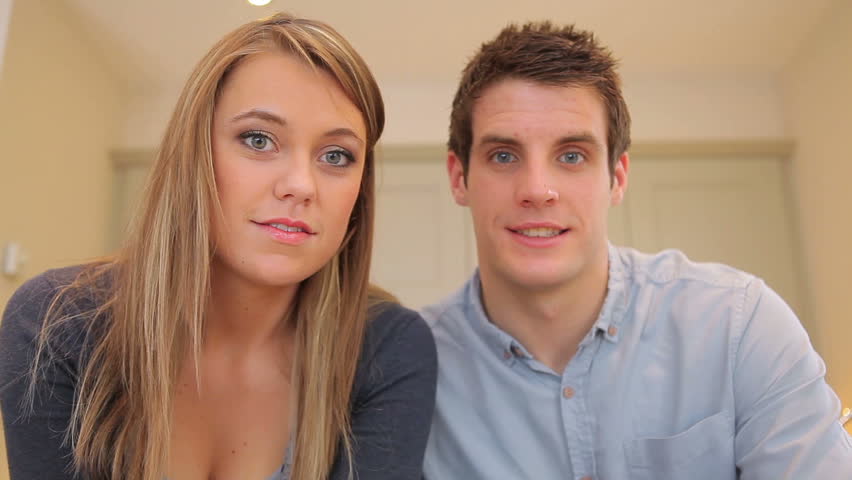 Couple waving and talking at video chat in kitchen