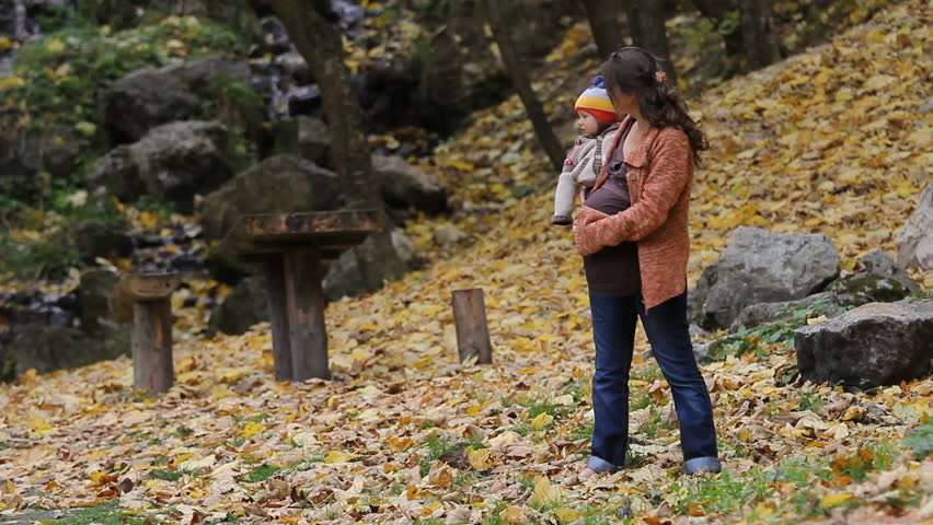 Mother holding and hugging her child in an autumnal scenery