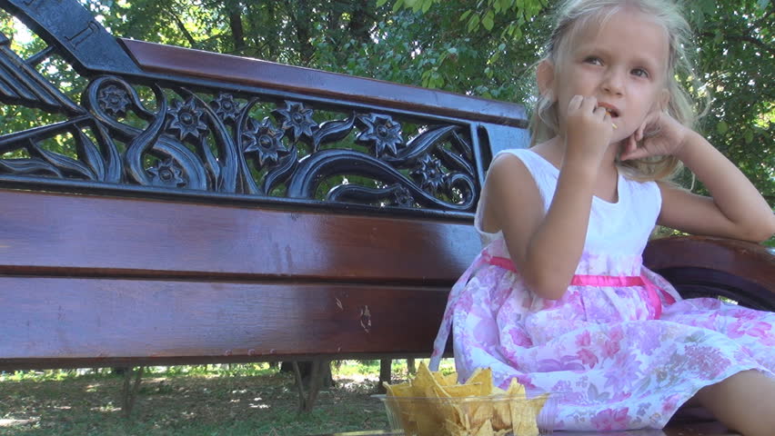Little Girl Eating Cornflakes on a Bench in Park