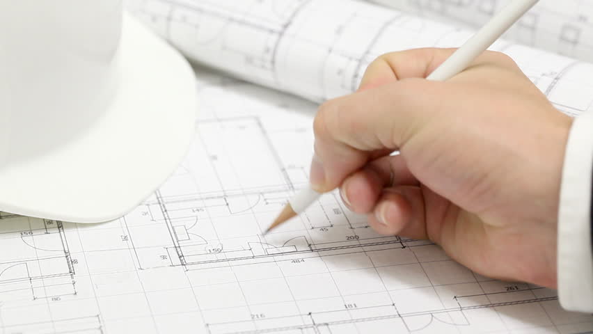 Male architect checking numbers on blueprint during house construction planing
