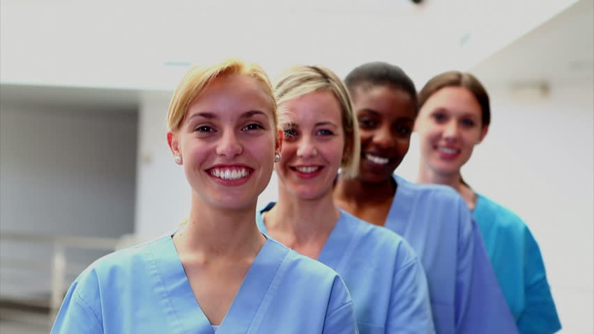 Smiling female nurses looking at camera in hospital hallway