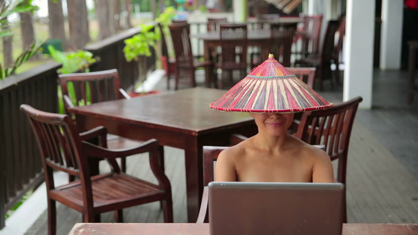 Asian freelance business woman at cafe with laptop and phone wearing an oriental hat