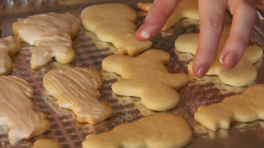 Baking Sugar Cookies 19. Preparing, mixing, baking and decorating Christmas sugar cookies. Brushing icing to the tops of the cookies.