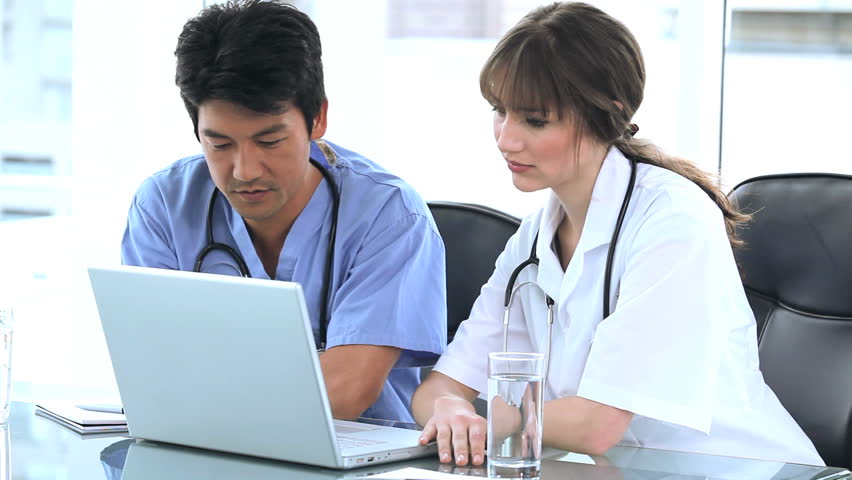 Serious practitioners talking together in front of a laptop in a bright room