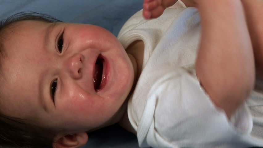 Baby laying on a blanket puts her foot in her mouth
