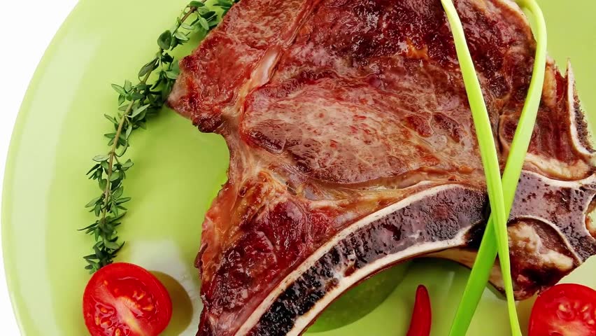 savory : roasted beef spare rib on green dish with cutlery thyme pepper and tomato isolated over white background