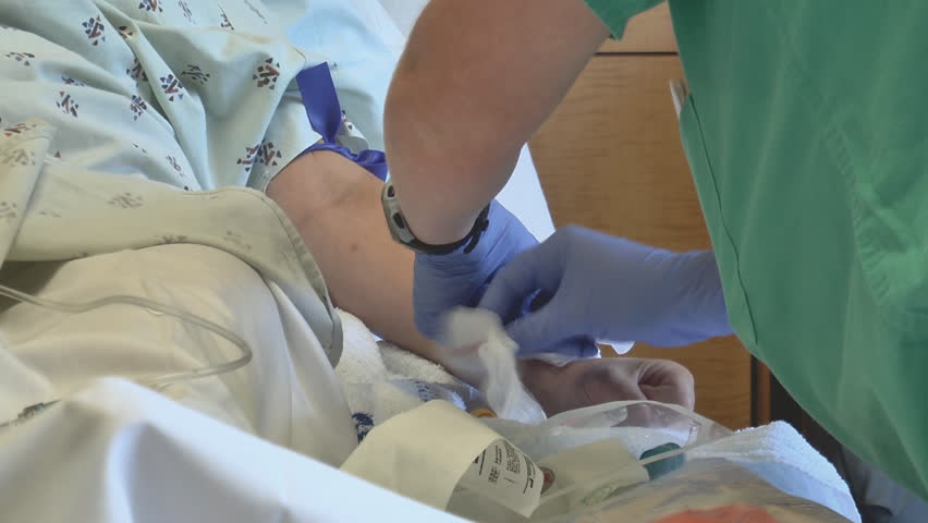 A nurse draws vials of blood from a patient's arm