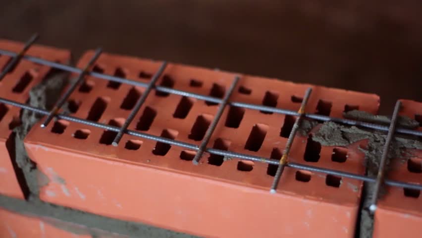 Metalware lattice on brick wall under construction, closeup in panoramic motion