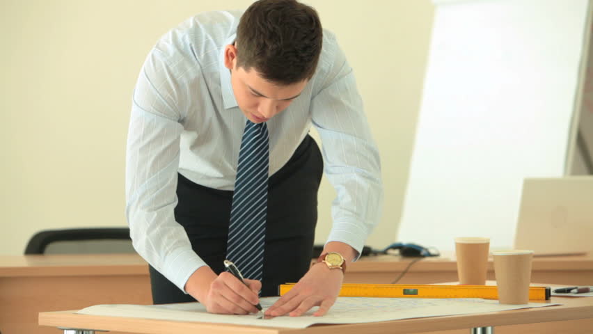 Zoom out of a young office worker being occupied with engineering
