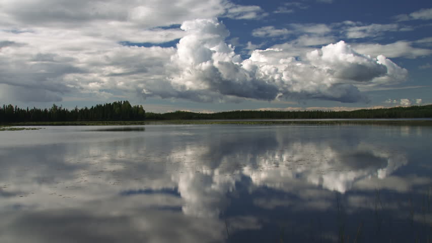 Expressive and dynamic cumulus storm clouds moving over an Alaskan lake on a windy afternoon.