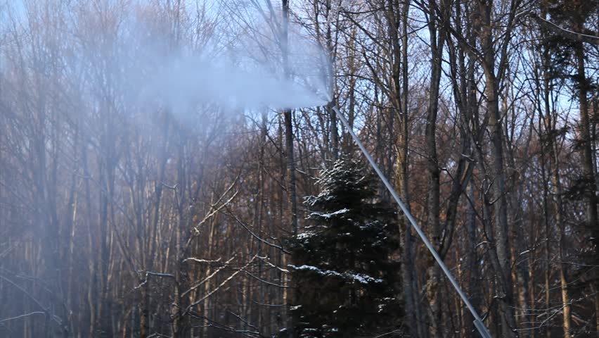 Snow cannon with forrest trees in background - downward motion