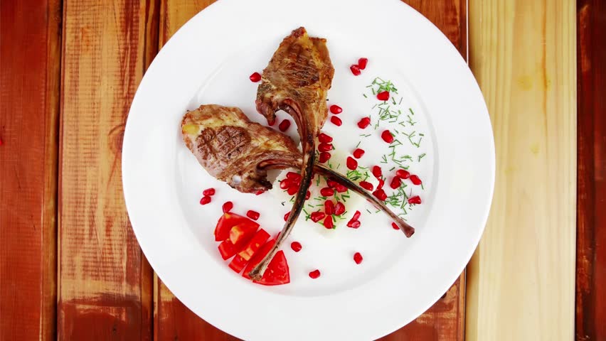 meat food: ribs on white with rice garnish and tomatoes over wood