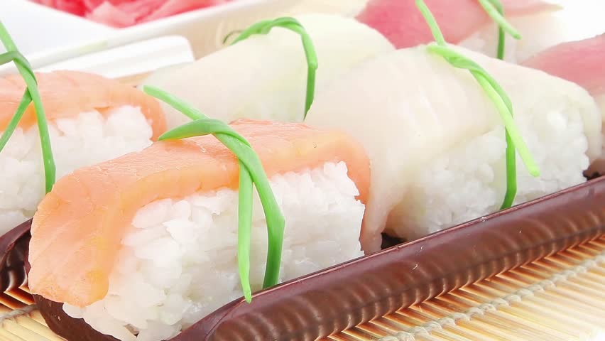 Japanese traditional cuisine - Different Types of Nigiri Sushi : Tuna (maguro) Salmon (sake) and Eel (unagi) with Wasabi and Ginger on bamboo mat isolated over white background